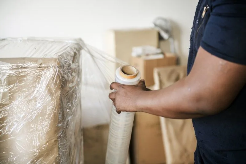 Staff member wrapping a packed piece of furniture with a roll of stretch film