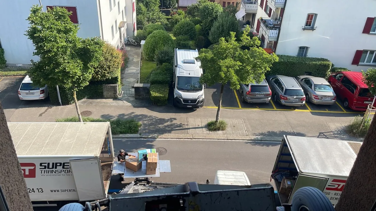 Blick von oben: Mitarbeiter von Super Transport laden Kartons und Möbel in die Umzugswagen